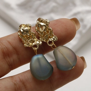 Vue détaillée des boucles d'oreilles en verre dépoli bleu mat et détails en métal doré