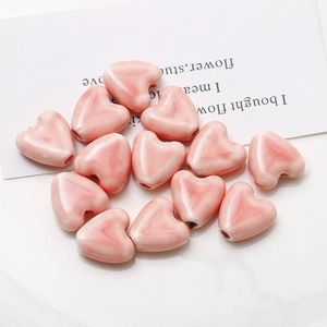 Détail macro de perles en céramique rose en forme de cœur avec texture marbrée pour bijoux