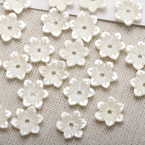 Macro detail of white resin flower charms with six petals and center hole for DIY jewelry