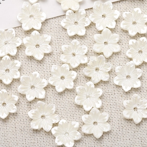 Macro detail of white resin flower beads with pearl finish and center hole for DIY jewelry