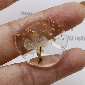 Handmade clear resin pendant with embedded dried flowers and gold foil accents