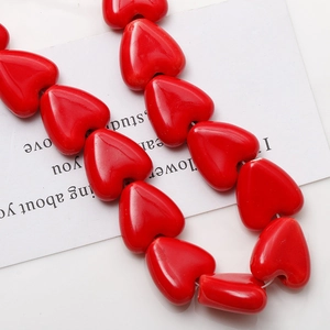 Gros plan de perles en céramique rouges brillantes en forme de cœur pour bijoux DIY