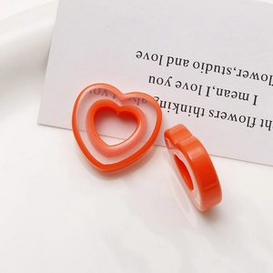 Detail showing orange layered heart resin charms on a white ceramic plate for DIY jewelry
