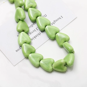 Vue macro de perles en céramique vert clair en forme de cœur pour bijoux DIY