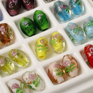 Macro detail of oval glass beads with 3D floral accents and gold foil flakes
