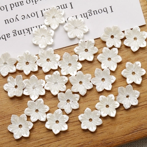 Macro view of white resin flower charms with central drill hole for DIY jewelry making