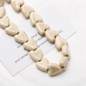 Gros plan de perles en céramique cœur crème brillant pour création bijoux et colliers