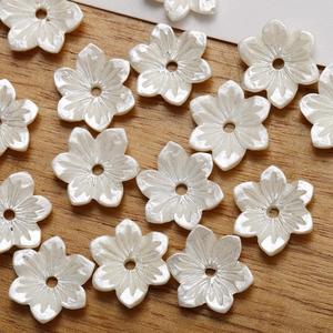 Macro detail of white six-petal resin flower beads with pearlescent finish for DIY jewelry
