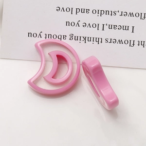 Macro view of two pink resin crescent moon charms with hollow design for jewelry making