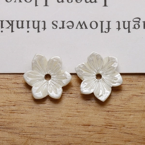 Close-up of white pearlescent resin flower beads for DIY jewelry making and crafts