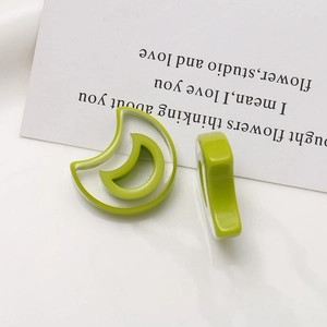 Detail of bright green resin crescent moon charms for DIY earrings on white background