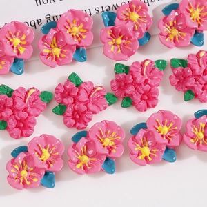 Macro detail of glossy resin pink flower charms with green leaves for DIY hair accessories