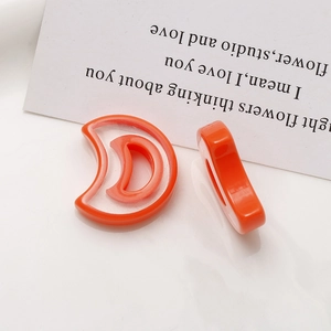 Macro view of orange resin crescent moon charms showing smooth edges and hollow design