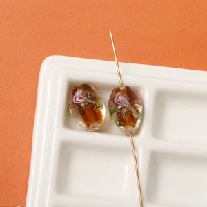 Detailed view of handmade oval glass beads with floral gold foil inlay for DIY jewelry