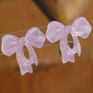 Detail of light purple translucent resin bow earrings with a soft pearlescent texture