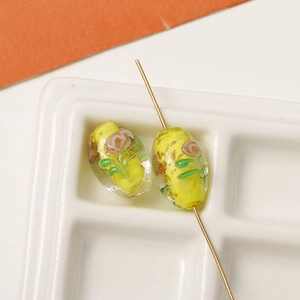 Macro detail of handmade oval glass bead with yellow core and floral lampwork patterns