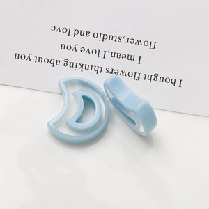 Macro detail of two light blue translucent crescent moon resin earring pendants