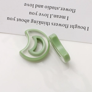 Macro detail of crescent moon resin jewelry components in translucent grass green