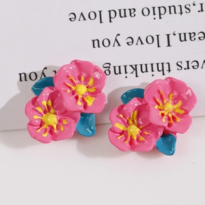 Macro shot of glossy pink flower resin earrings with yellow centers and blue leaves