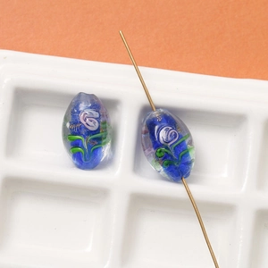 Macro view of blue lampwork glass beads with floral gold leaf patterns for DIY jewelry