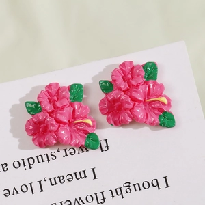 Macro view of pink resin flower charms with green leaves and yellow stamens for DIY