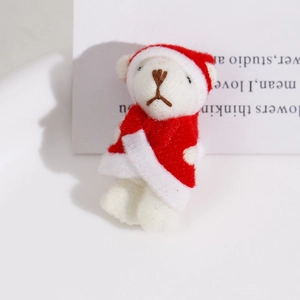 Close-up of a mini Christmas plush bear wearing a red Santa outfit in a ceramic tray