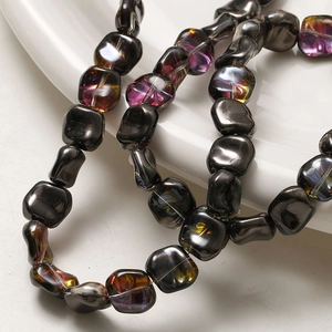 Détail macro de perles cubiques en verre irisé et galets métalliques pour bijoux DIY