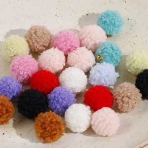 Gros plan de pompons colorés en peluche avec anneaux dorés pour création de bijoux