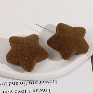 Detailed macro view of dark brown flocked star-shaped DIY jewelry charms on a white stone tray