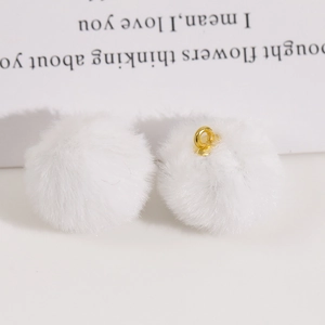 Detail of soft 20mm white faux fur pom-poms with golden metal loops for DIY jewelry making