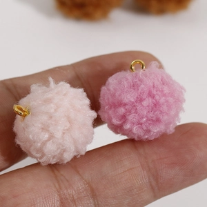 Détail de pompons en peluche rose avec boucles dorées pour la création de bijoux