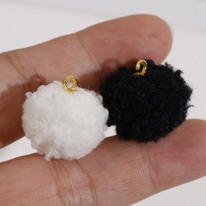 Vue rapprochée de pendentifs pompons en fourrure noir et blanc avec anneaux dorés