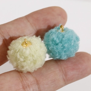 Détail de pompons jaunes et bleus avec anneaux dorés pour la création de bijoux DIY