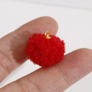 Gros plan d'un pompon rouge duveteux avec anneau doré pour la création de bijoux DIY