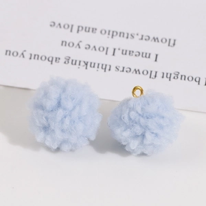 Gros plan de pompons duveteux bleu clair avec anneaux dorés pour la création de bijoux