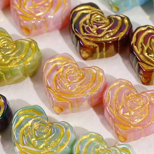 Close-up of heart-shaped beads with gold-rimmed rose patterns for DIY jewelry making