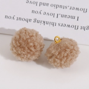 Gros plan de pompons en peluche beige avec anneaux dorés pour la création de bijoux DIY
