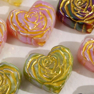 Detailed macro shot of heart-shaped resin beads with golden embossed rose patterns