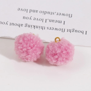 Détail de breloques pompons roses duveteux avec anneaux dorés pour création de bijoux