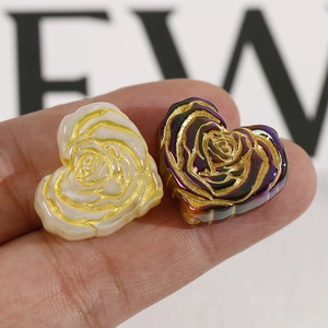 Macro detail of heart-shaped resin beads with golden rose relief for DIY jewelry