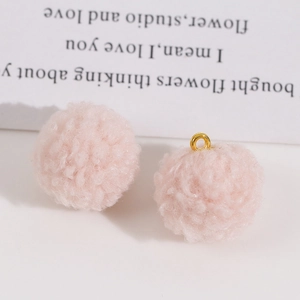 Vue macro de breloques pompons en fausse fourrure rose avec anneaux dorés pour bijoux