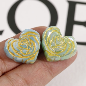 Macro detail of heart-shaped rose beads with gold-painted edges in blue and green
