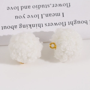 Gros plan de pompons blancs en peluche avec boucles dorées pour la création de bijoux