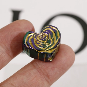 Macro detail of heart-shaped bead with golden rose pattern and colorful gradient finish