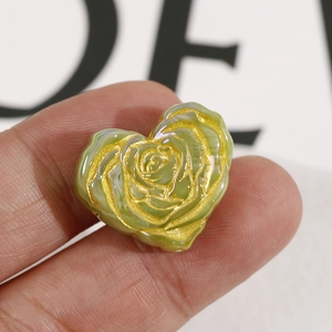 Macro shot of heart-shaped light green rose bead with golden accents for DIY jewelry