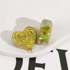 Macro view of heart-shaped translucent green beads featuring golden rose patterns