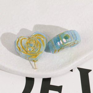 Detailed macro view of sky blue heart beads with gold rose carvings for DIY jewelry