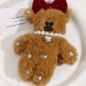 Close-up of brown plush bear with red velvet bow and pearl necklace accessories