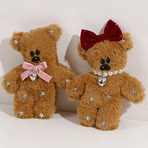 Close-up of plush teddy bear charms with velvet bows, pearls and silver star sequins