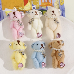 Detail of colorful plush bears with pearl necklaces and stars in a white tray